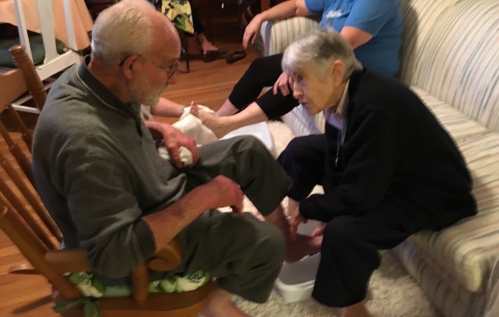 Sister of Charity Marie de Paul Combo washes the feet of Christian Br. Louis Rodemann, longtime leader at Kansas City's Holy Family Catholic Worker House, during a Holy Thursday Seder service. Combo died April 1 at age 99. (Courtesy of Thomas C. Fox)